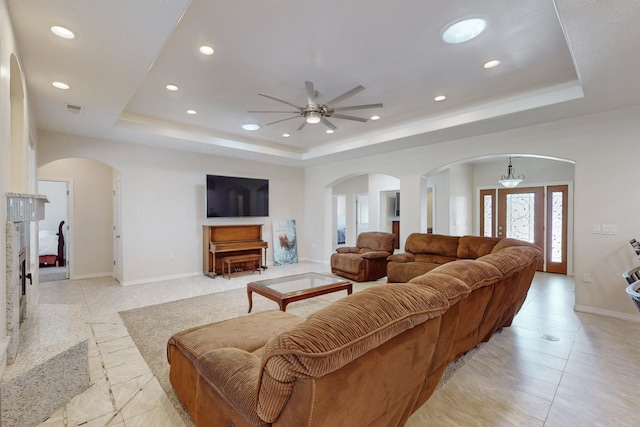 living room featuring ceiling fan, a premium fireplace, and a raised ceiling