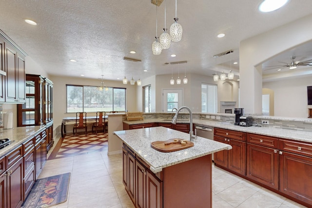 kitchen with a kitchen island, a textured ceiling, light stone counters, and decorative light fixtures