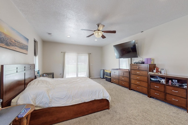 carpeted bedroom featuring ceiling fan and a textured ceiling