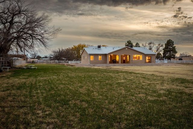 back house at dusk featuring a yard