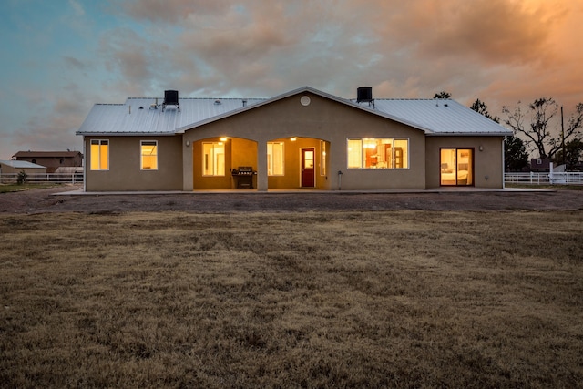 back house at dusk with a lawn