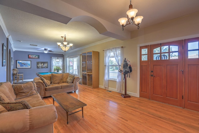 living room with a wealth of natural light, crown molding, and light wood-type flooring