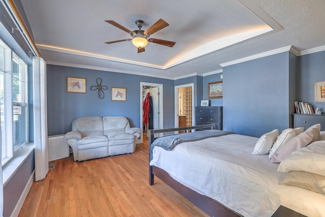 bedroom featuring ceiling fan, crown molding, a spacious closet, light hardwood / wood-style flooring, and a closet