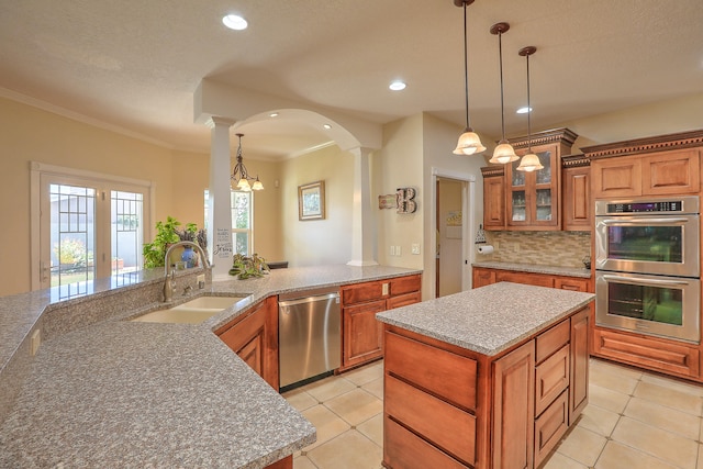 kitchen with light tile patterned flooring, appliances with stainless steel finishes, a center island, and sink