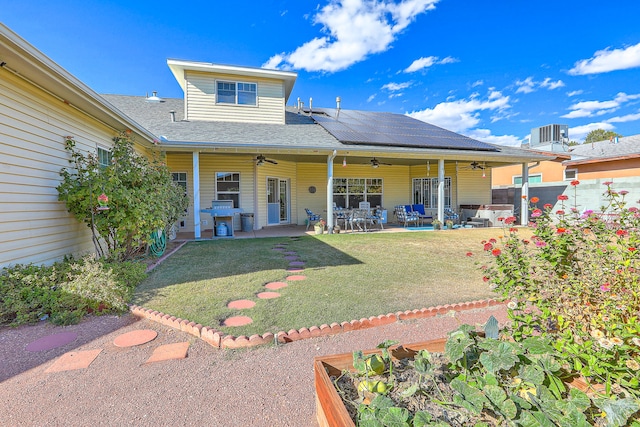 rear view of property featuring ceiling fan, a yard, solar panels, central air condition unit, and a patio area