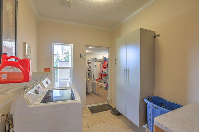 clothes washing area featuring light tile patterned flooring, ornamental molding, a textured ceiling, and washing machine and clothes dryer