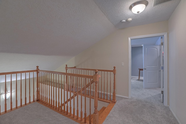 interior space with light colored carpet, a textured ceiling, and vaulted ceiling