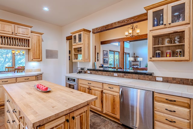 kitchen with stainless steel oven, light brown cabinets, tile countertops, a notable chandelier, and a kitchen island