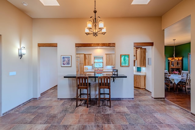 kitchen with a kitchen bar, kitchen peninsula, a skylight, an inviting chandelier, and hanging light fixtures