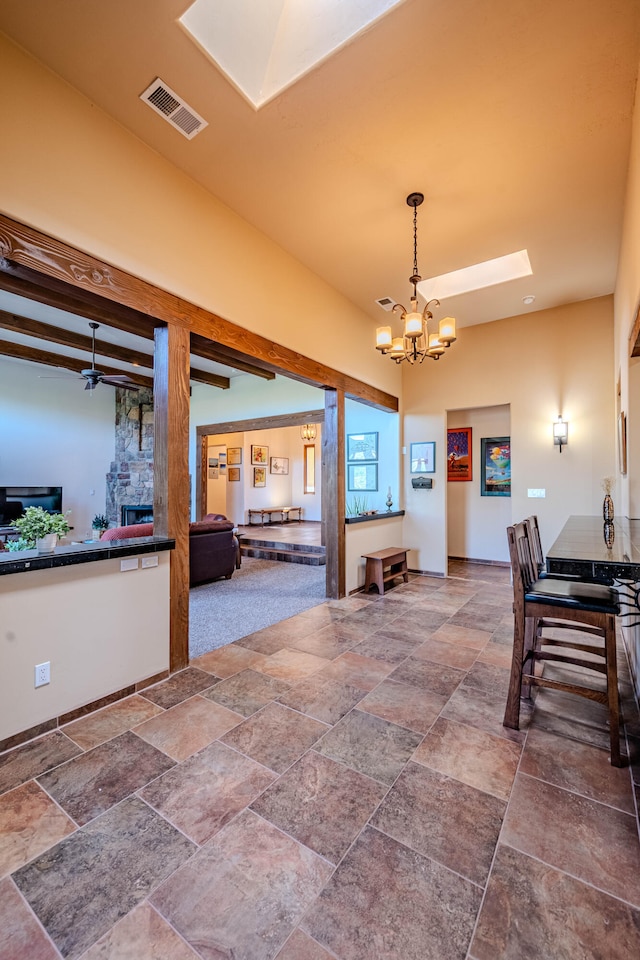 dining space with beamed ceiling, ceiling fan with notable chandelier, and a fireplace