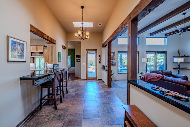 foyer entrance featuring ceiling fan with notable chandelier, beam ceiling, a towering ceiling, and a wealth of natural light