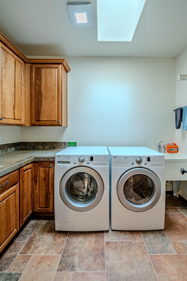 washroom featuring cabinets, independent washer and dryer, sink, and a skylight