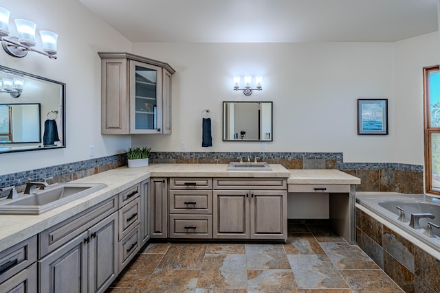 bathroom with vanity, an inviting chandelier, and tiled tub