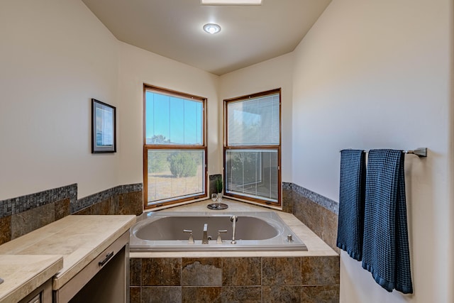 bathroom with tiled tub and vanity