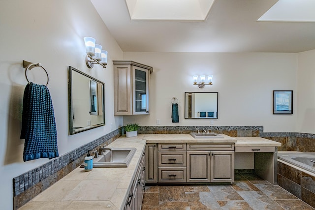 bathroom featuring a chandelier, vanity, a skylight, and a relaxing tiled tub