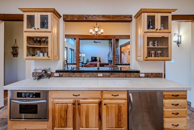 bar with tile countertops, hanging light fixtures, ceiling fan with notable chandelier, and appliances with stainless steel finishes