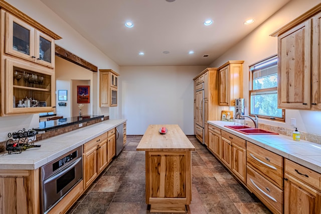 kitchen with sink, wooden counters, kitchen peninsula, oven, and a kitchen island