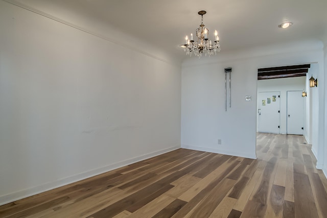 spare room featuring a notable chandelier and dark hardwood / wood-style floors