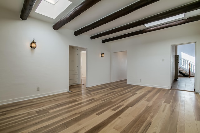 unfurnished living room with beam ceiling, wood-type flooring, and a skylight