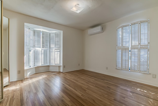 empty room featuring hardwood / wood-style floors and a wall mounted air conditioner