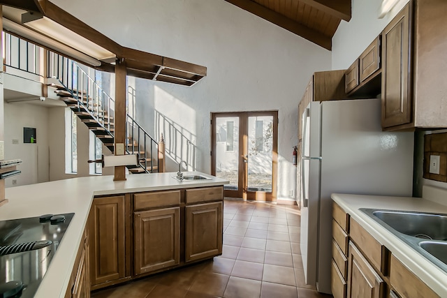 kitchen featuring french doors, sink, light tile patterned floors, beam ceiling, and kitchen peninsula