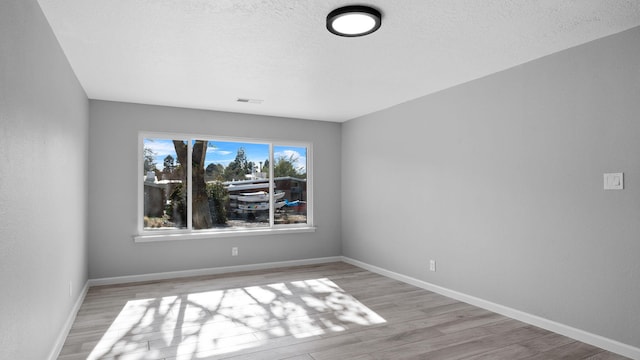 spare room featuring a textured ceiling and light wood-type flooring