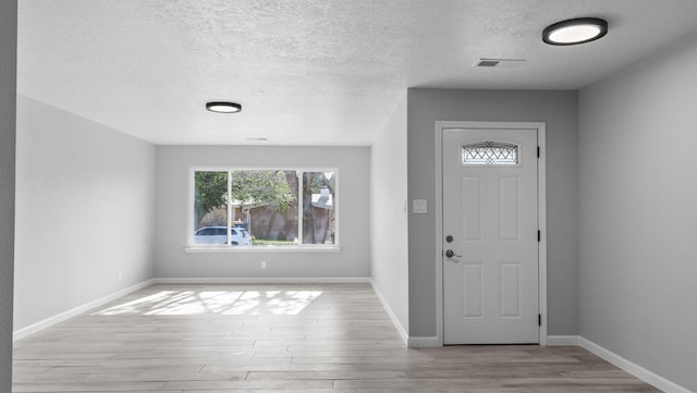 entryway with a textured ceiling and light hardwood / wood-style flooring