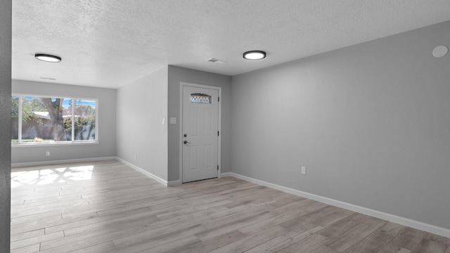 foyer with light hardwood / wood-style floors and a textured ceiling