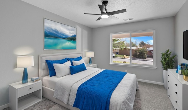 bedroom with ceiling fan, light colored carpet, and a textured ceiling