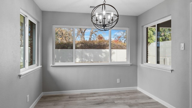 unfurnished dining area featuring a notable chandelier and light wood-type flooring