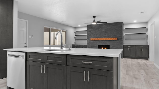 kitchen featuring stainless steel dishwasher, light hardwood / wood-style floors, sink, and a kitchen island with sink