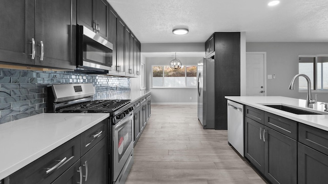 kitchen featuring decorative backsplash, appliances with stainless steel finishes, sink, an inviting chandelier, and hanging light fixtures