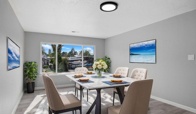 dining room featuring wood-type flooring and a textured ceiling