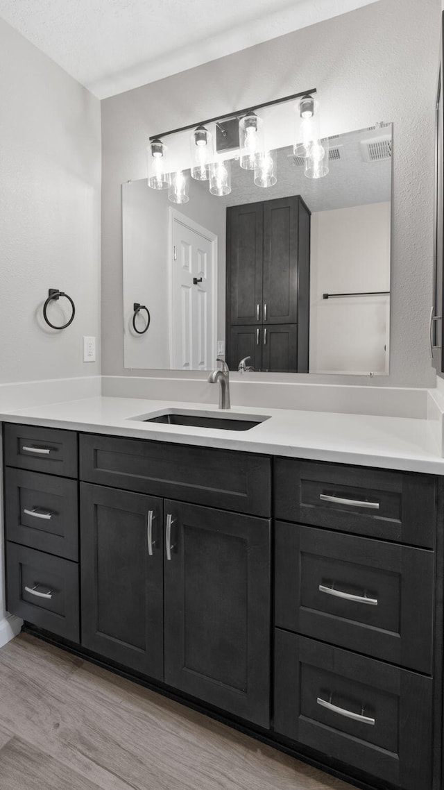 bathroom with hardwood / wood-style floors, vanity, and a textured ceiling