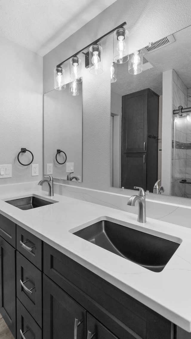 bathroom featuring vanity, a textured ceiling, and an enclosed shower