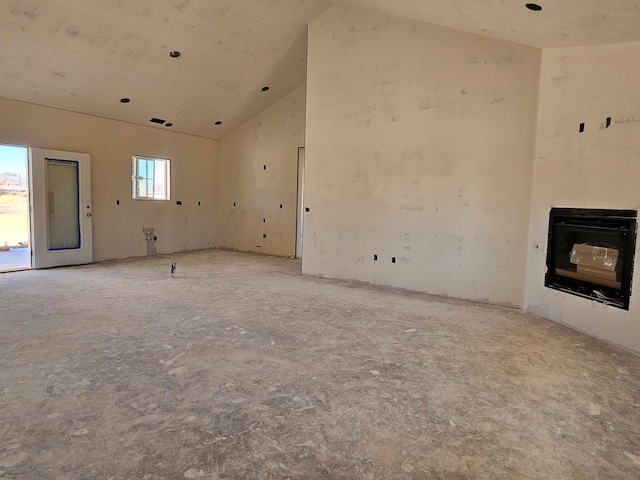 unfurnished living room with high vaulted ceiling and a glass covered fireplace