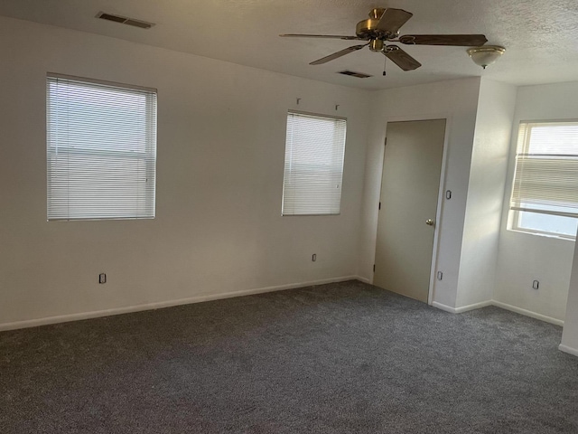 empty room with ceiling fan and dark carpet