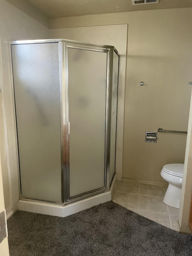 bathroom with tile patterned flooring, toilet, and a shower with door