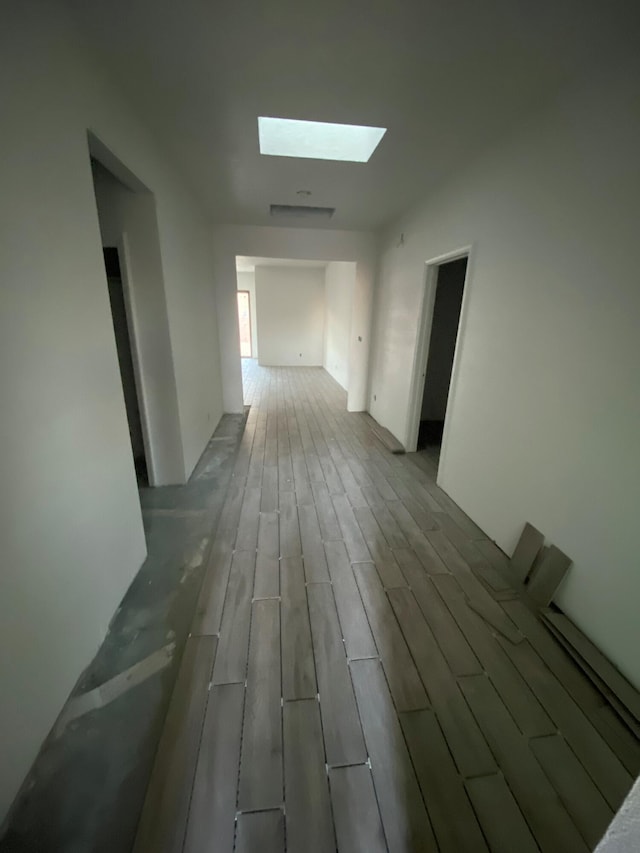 hall with light wood-type flooring and a skylight