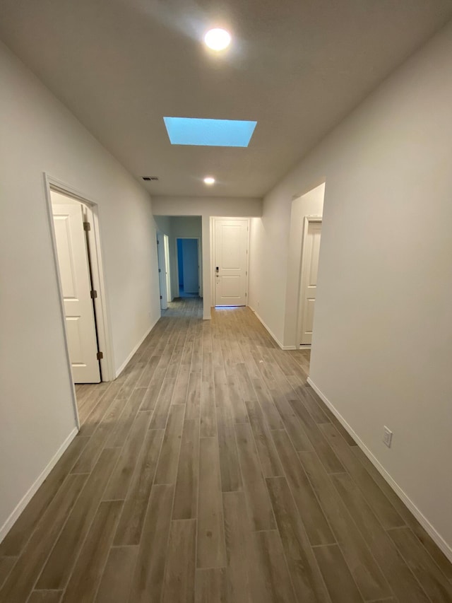 corridor featuring wood-type flooring and a skylight