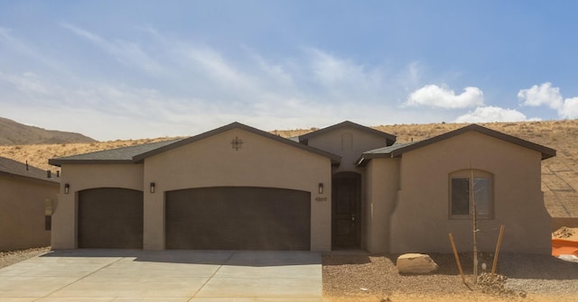 view of front of house featuring concrete driveway, a mountain view, an attached garage, and stucco siding