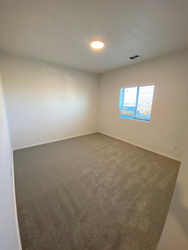 spare room featuring dark colored carpet