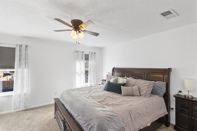 carpeted bedroom featuring ceiling fan and a textured ceiling