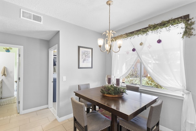 dining area featuring light tile patterned flooring, a notable chandelier, and a textured ceiling