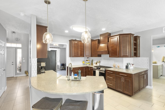 kitchen with a breakfast bar, appliances with stainless steel finishes, kitchen peninsula, pendant lighting, and decorative backsplash