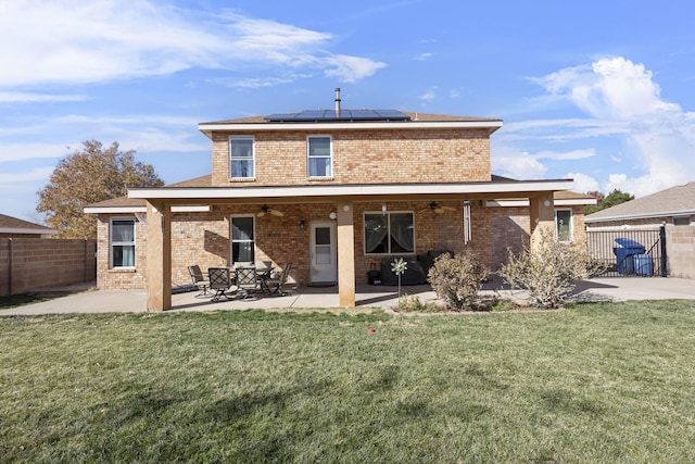 rear view of property featuring a yard, a patio, and solar panels