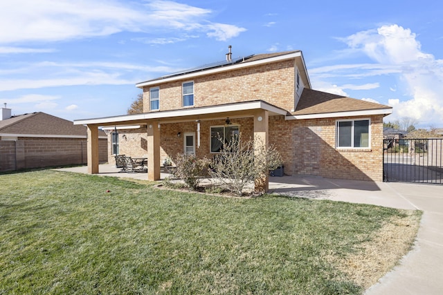 back of property with a lawn, a patio area, and solar panels