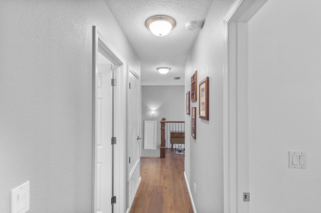 corridor with dark wood-type flooring and a textured ceiling