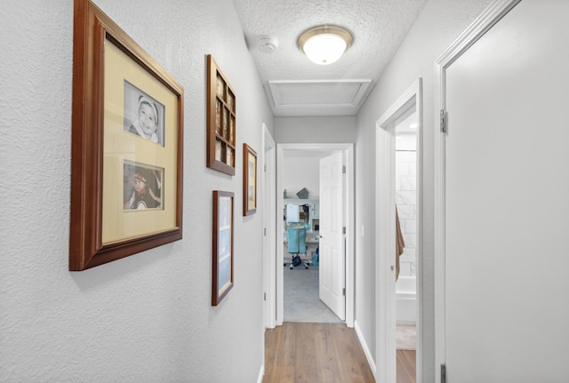 hall with wood-type flooring and a textured ceiling