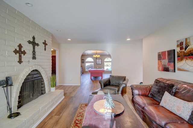 living area featuring wood finished floors, baseboards, a fireplace, recessed lighting, and arched walkways